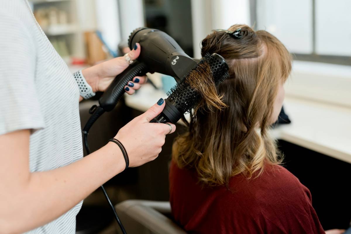woman creating base ponytail for bubble ponytail hairstyle